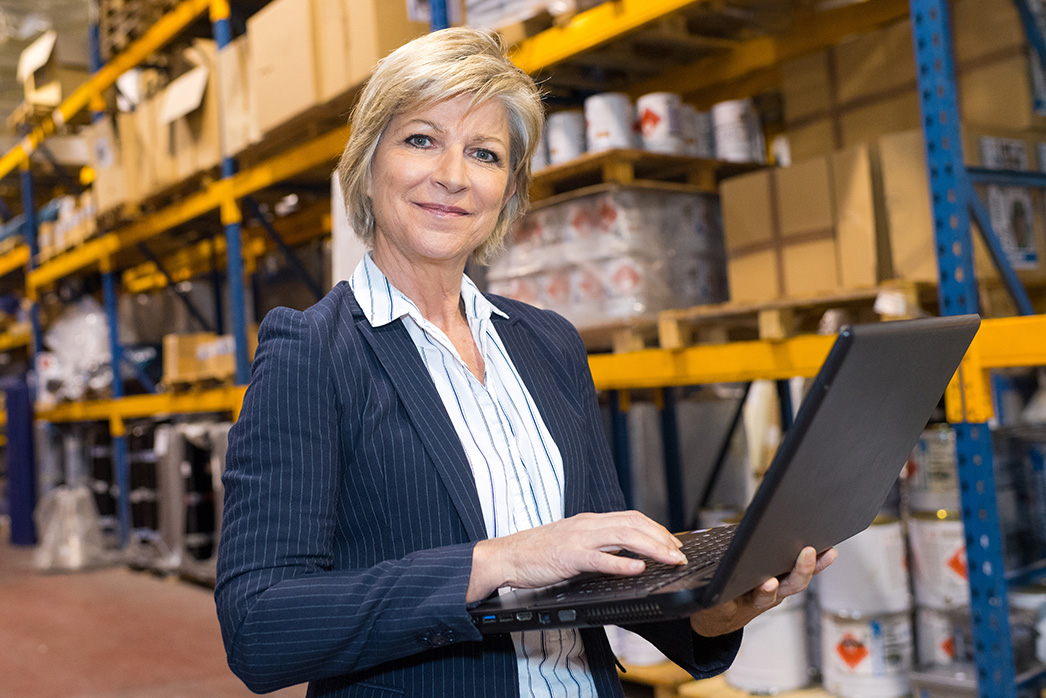 business woman working on a laptop inside a warehouse