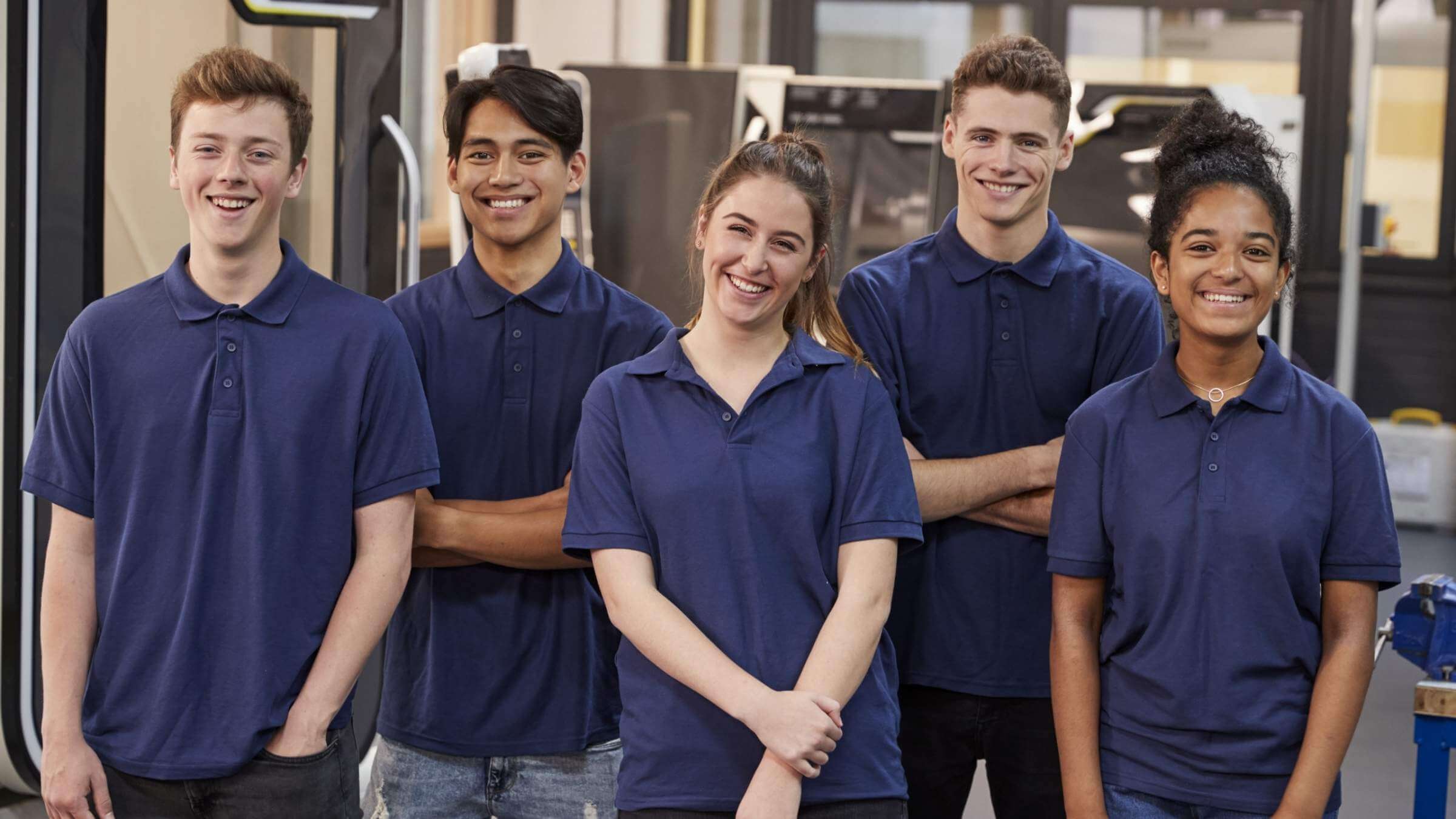 Eine Gruppe von fünf Jugendlichen stehen in einer Werkstatt für technische Geräte