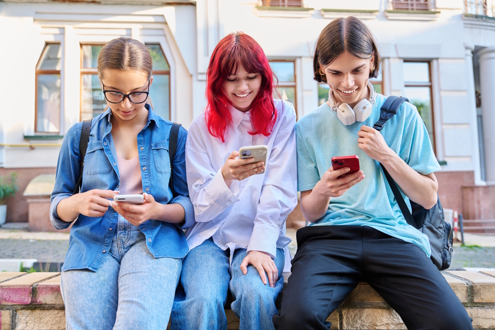 Drei Jugendliche schauen auf ihr Handy